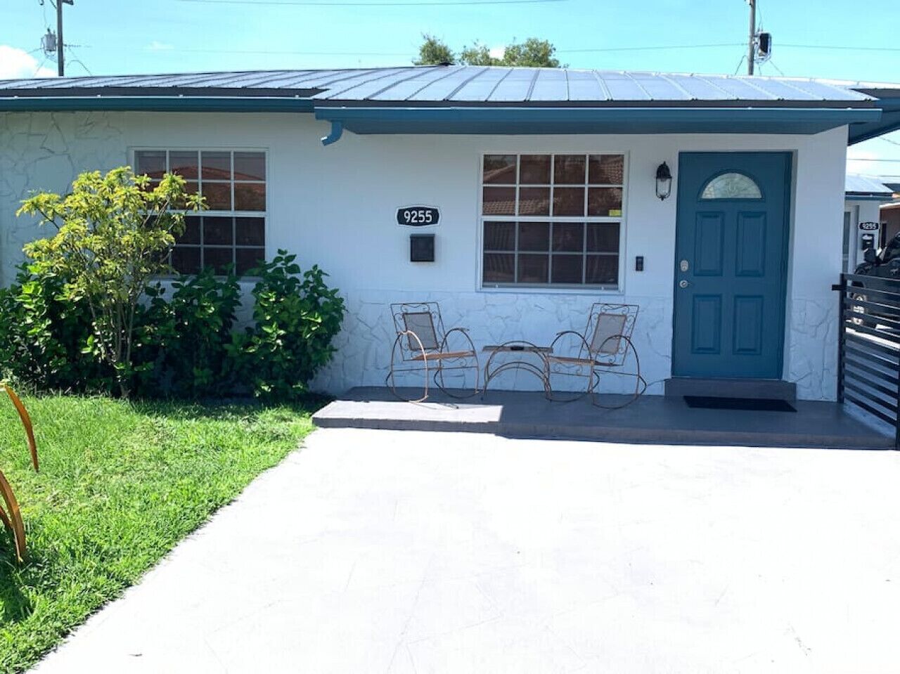 A single-story house with a blue door and a number '9255' on the wall.