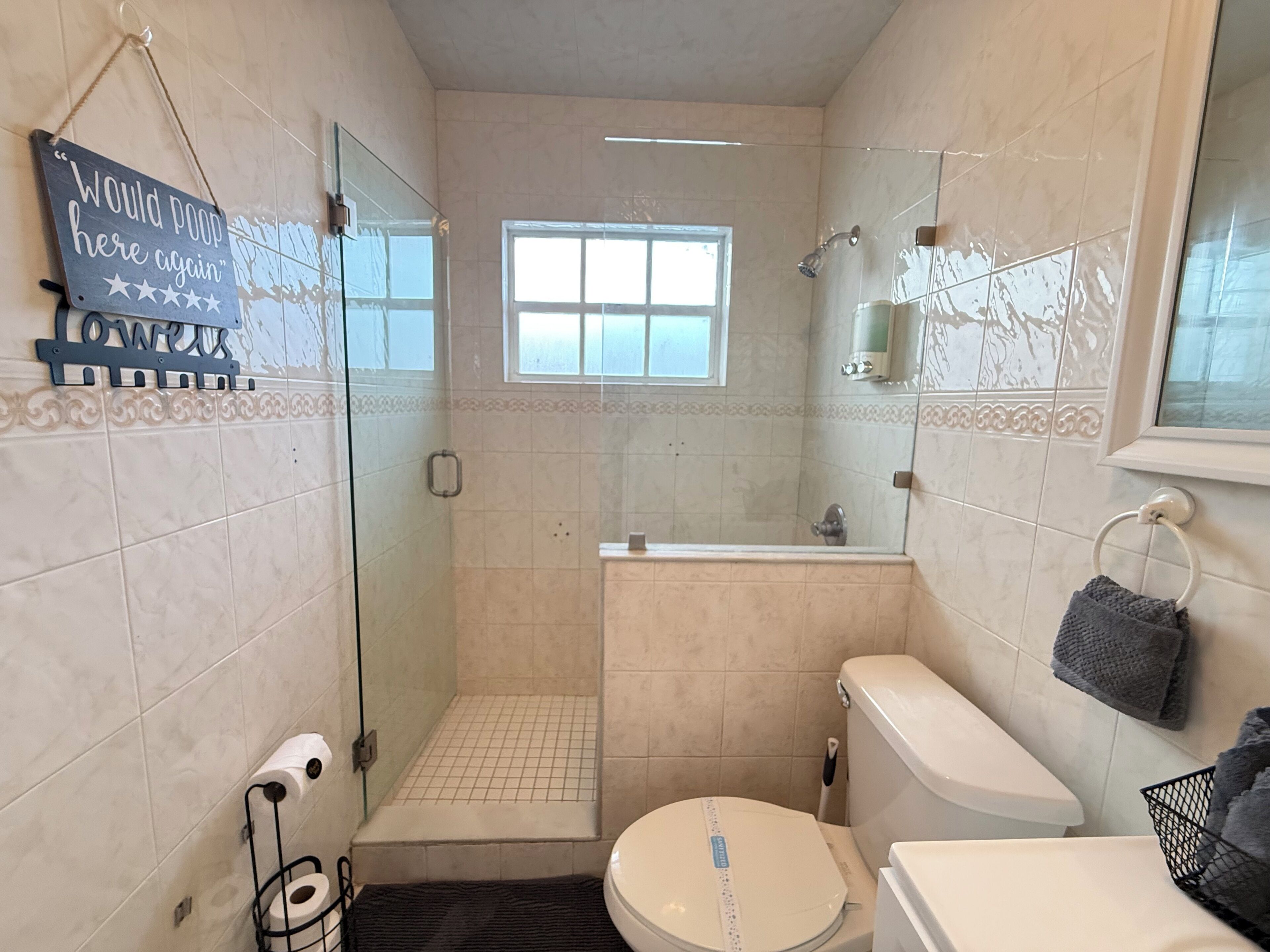 Ein Badezimmer mit Dusche, Toilette und einem Schild an der Wand.