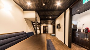 Un intérieur moderne avec une table et des bancs en bois, un escalier et un coin cuisine.