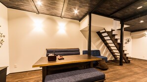 Un salon moderne avec une table à manger en bois, un banc recouvert d’un tissu bleu et un escalier avec des rampes en bois.