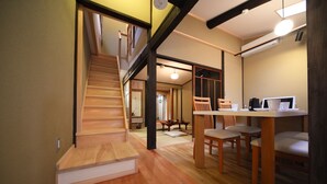 A modern kitchen with wooden flooring, a dining area with chairs, a staircase, and a built-in desk with a computer. - Kyomachiya Gion Miyagawatei (Kyoto)