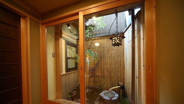 A traditional Japanese room with sliding doors, a small garden with a koi pond, and a bamboo fence. - Kyomachiya Gion Miyagawatei (Kyoto)