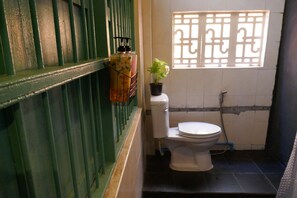 A small bathroom with a toilet, a green-framed window, and a potted plant. - 2Street Hostel at Surathani - Adults Only (Surat Thani)