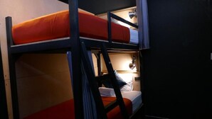 A bunk bed room with a ladder, a bedside lamp, and a small table. - 2Street Hostel at Surathani - Adults Only (Surat Thani)