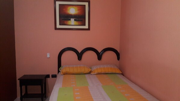 Una cama individual con cabecera, una mesita de noche y un cuadro enmarcado en la pared.