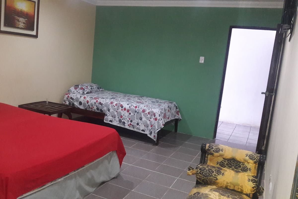 Una habitación con una cama, una cama individual, una silla y una puerta.