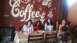 A group of people seated at a table with a wall mural that reads "Coffee time" and includes coffee cup illustrations. - Hotel Brisas del Pacifico (Playas)