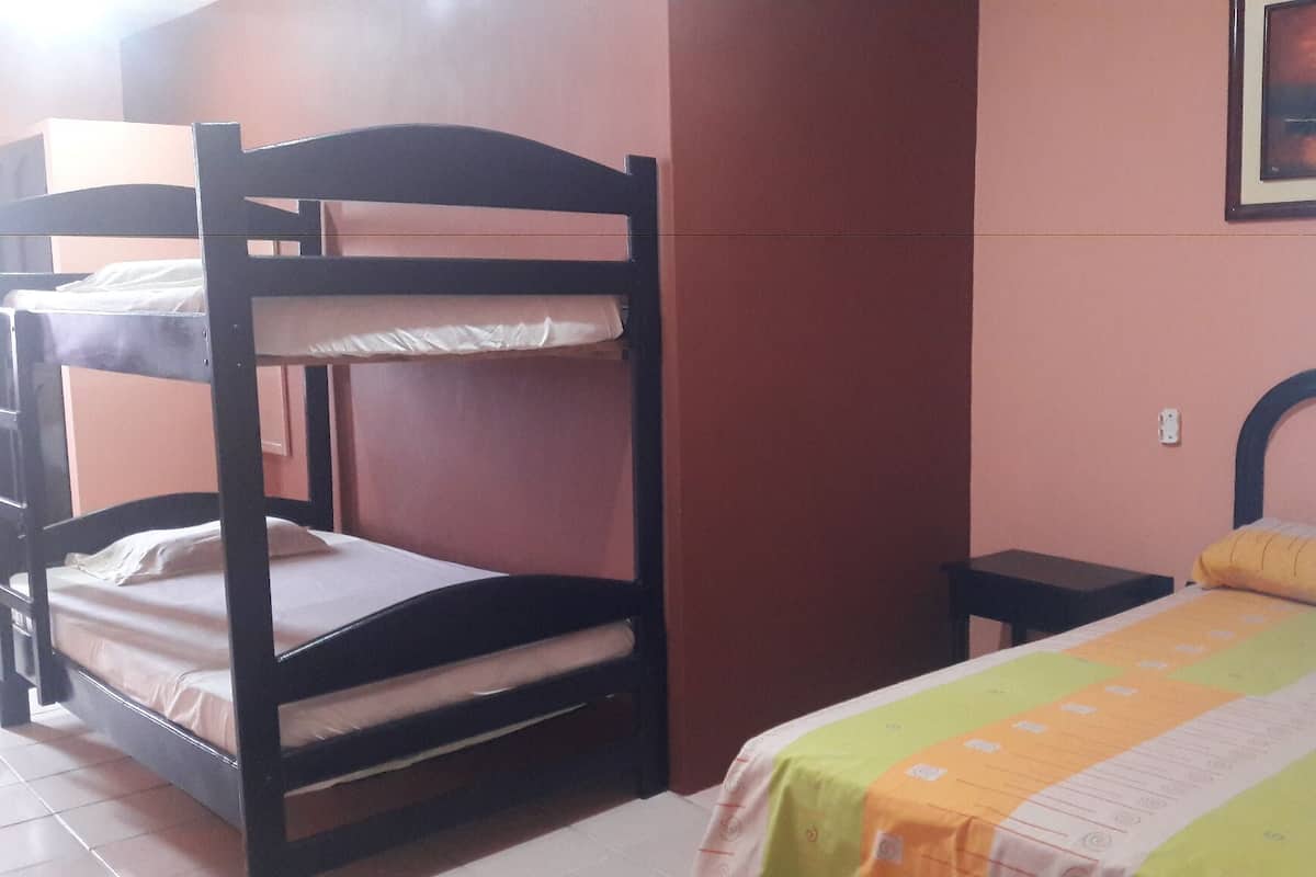 Habitación con literas, una cama individual y una mesita pequeña.