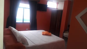 A room with a bed, a window with curtains, a television on the wall, and a door. - Hotel Brisas del Pacifico (Playas)