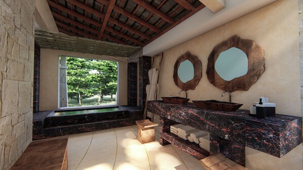 A bathroom with a stone countertop, two sinks, a wooden bench, and a large window with a view of trees.