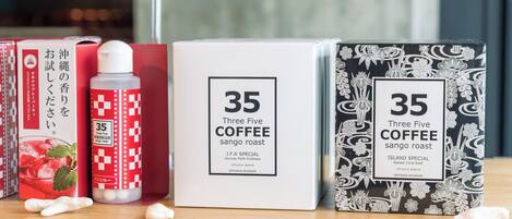 A shelf with three boxes of 'Three Five Coffee' and a bottle of 'J.F.K. Special' on a wooden surface.