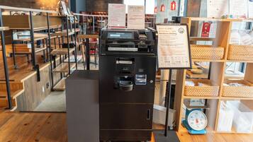 A self-check-in kiosk in a hotel lobby with wooden flooring and a scale on the right.