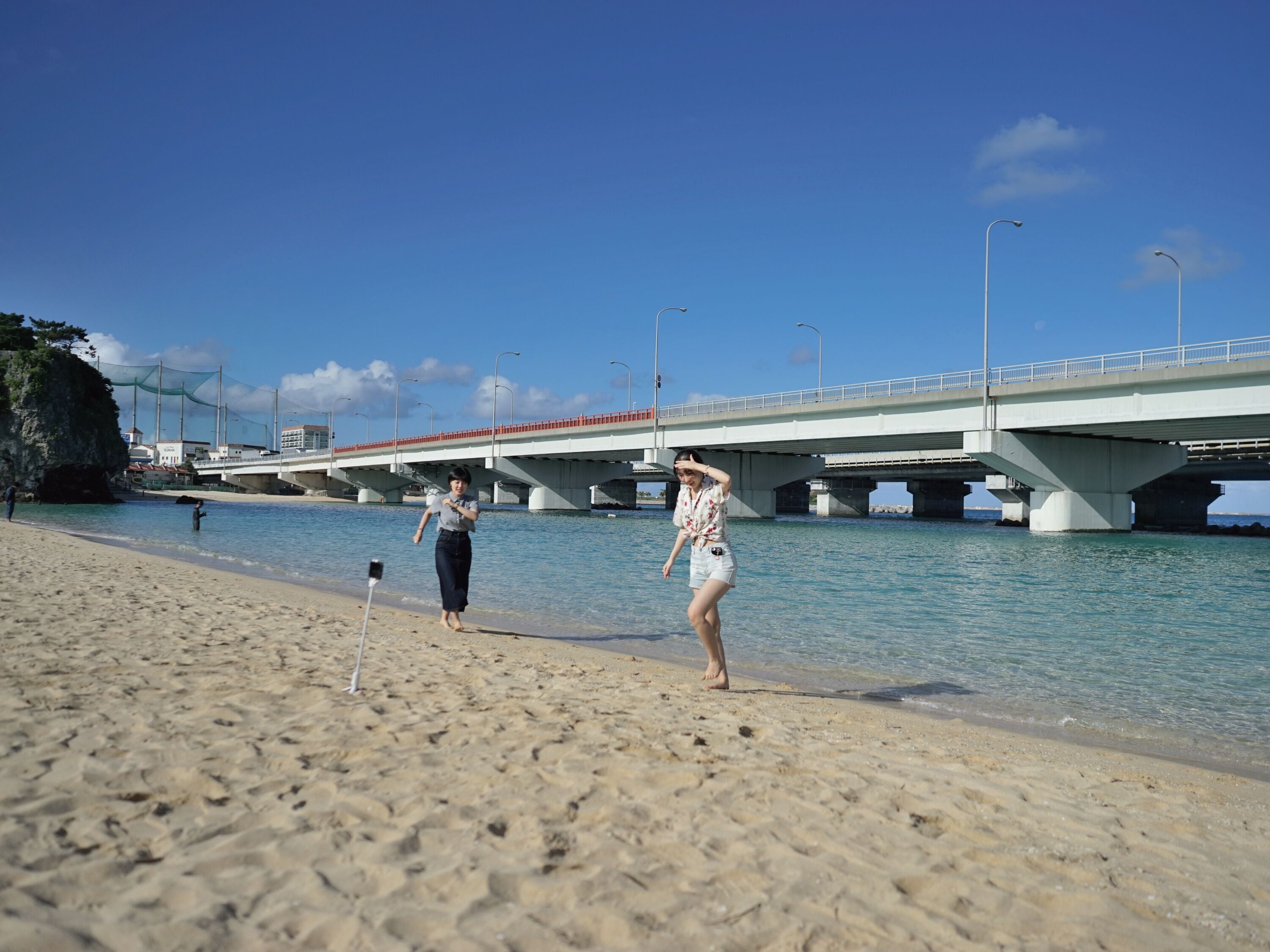 Una playa con un puente al fondo.