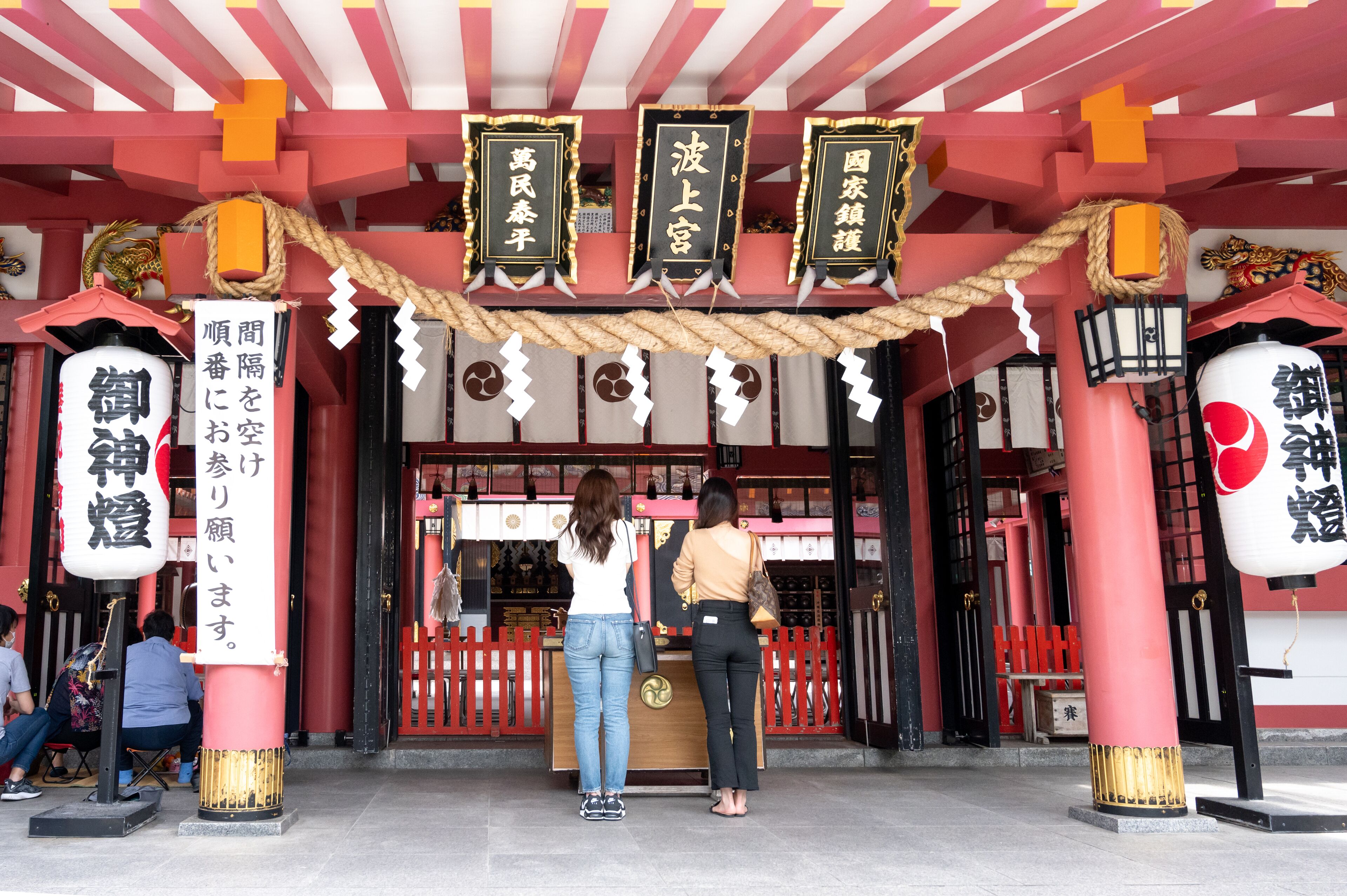 Een traditionele Japanse toegangspoort van een torii, met twee vrouwen ervoor.