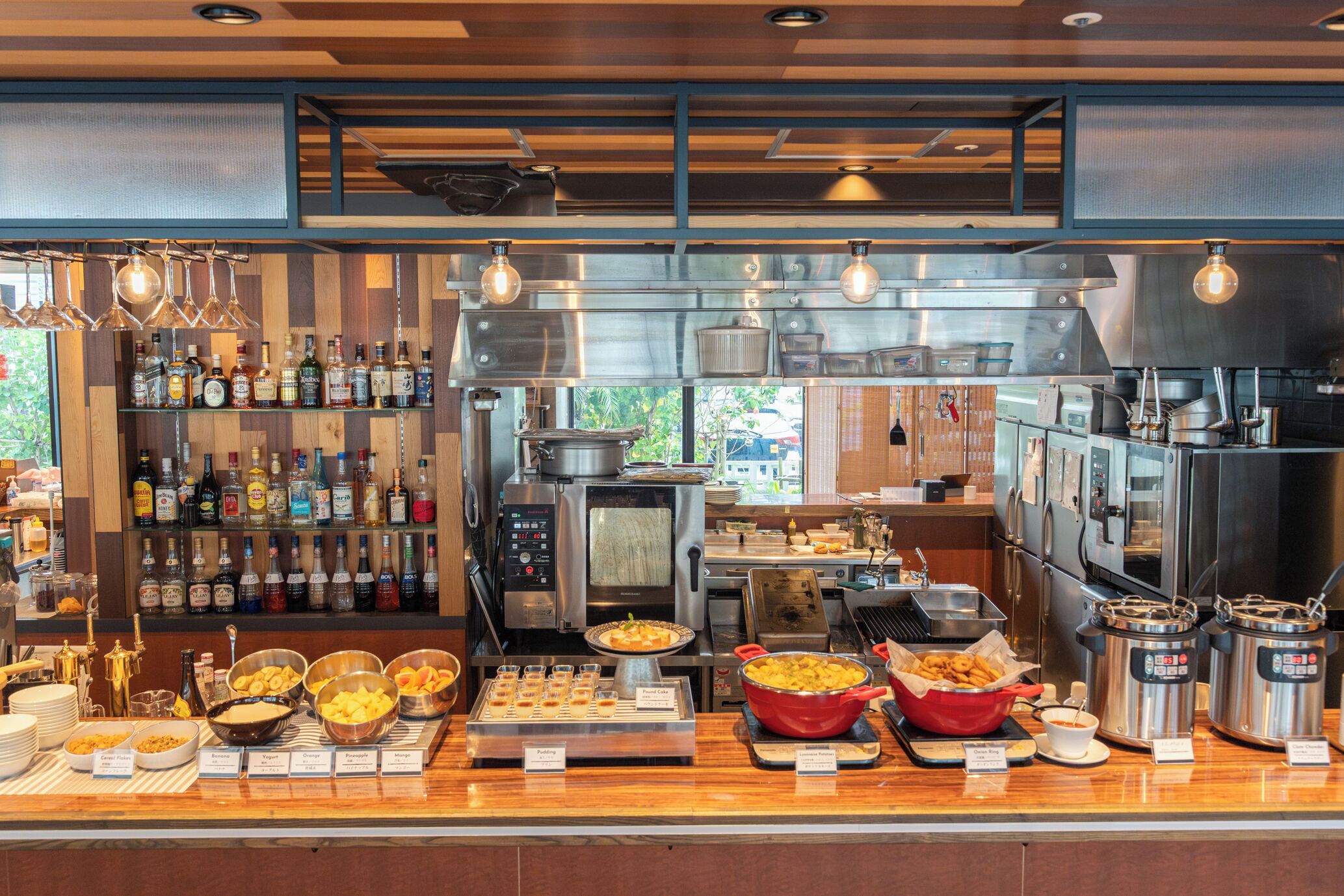 A buffet area with various food items, a selection of beverages, and kitchen equipment in the background.