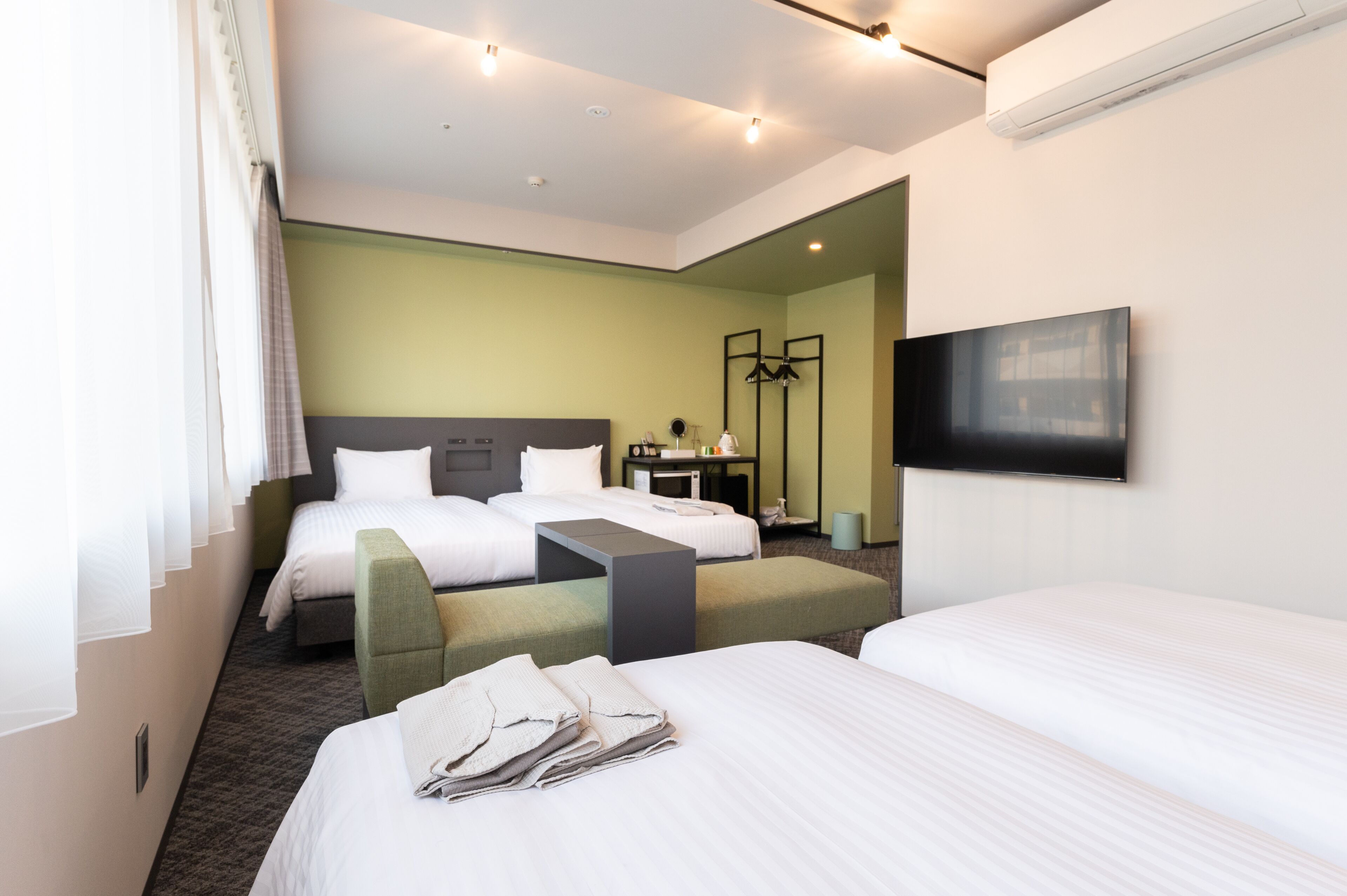 Une chambre d’hôtel avec deux lits, un bureau, une chaise, une télévision et un miroir.