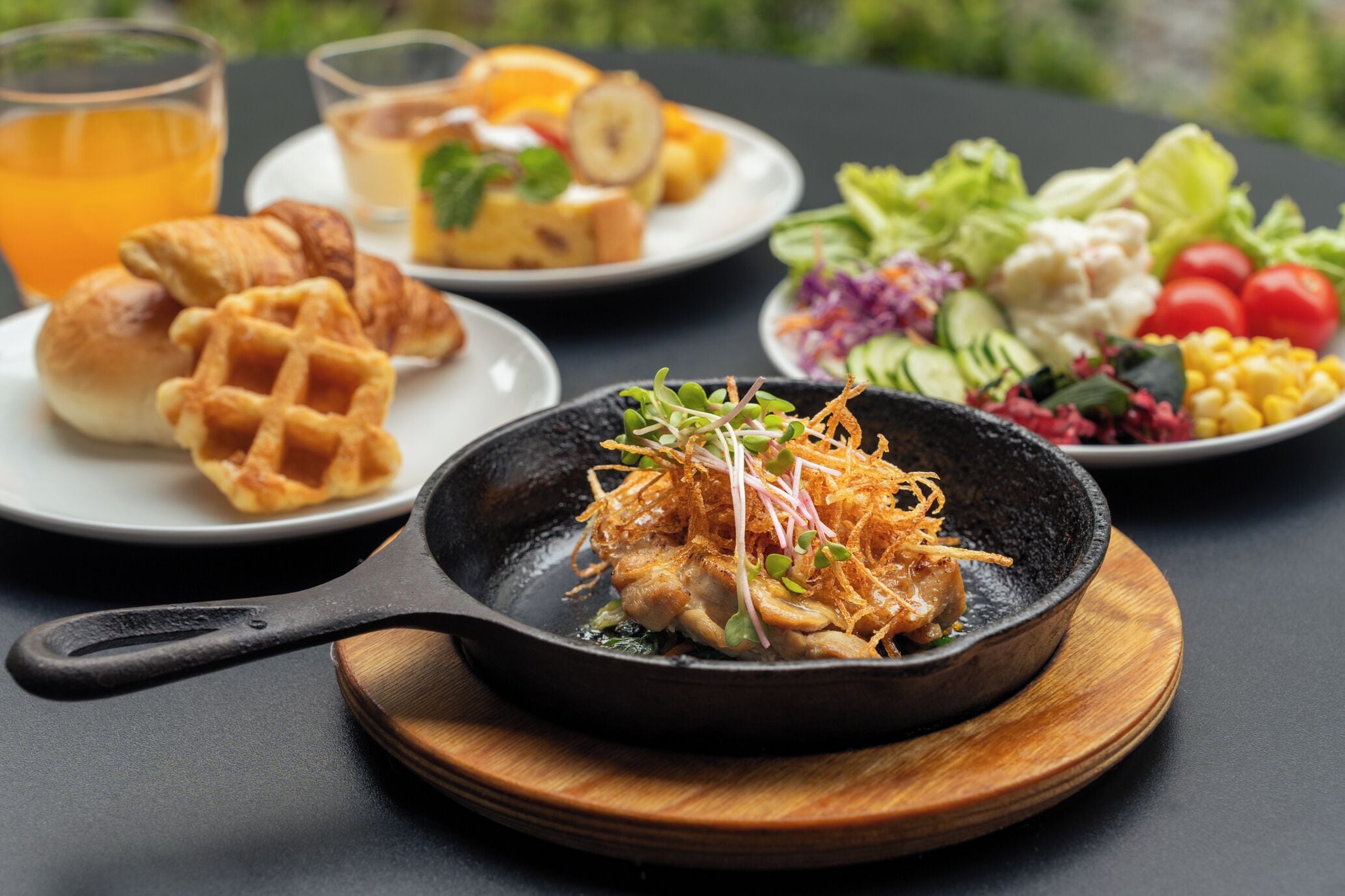 A meal with a skillet, salad, and bread on a table.