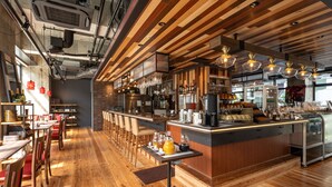 A modern restaurant interior with wooden floors, a bar area, and a kitchen visible through a glass partition. - Hotel Cocktail Stay Naha (Naha)