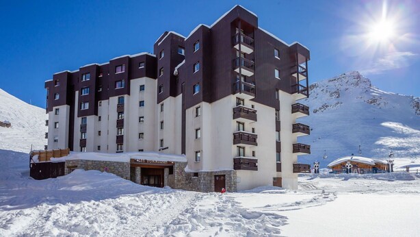 Un hôtel à plusieurs étages, doté d’une façade en pierre, situé dans une région montagneuse enneigée.