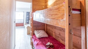 A bunk bed with a wooden headboard, a red blanket, and slippers on the lower bunk. - Lovely apartment for 4 people with WIFI, TV and balcony (Les Boisses)