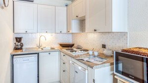 A compact kitchen with white cabinets, a built-in dishwasher, a coffee maker, a stove, and a microwave. - Lovely apartment for 4 people with WIFI, TV and balcony (Les Boisses)