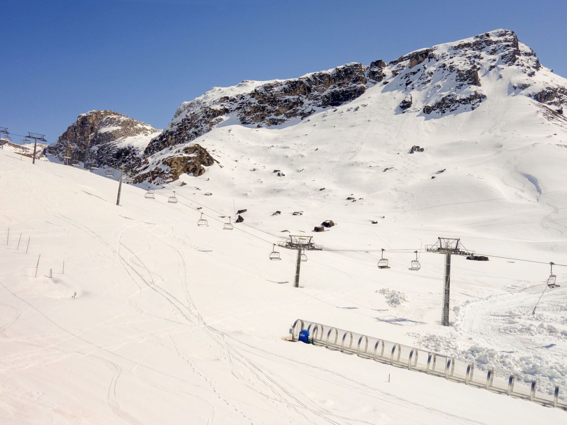 A snow-covered mountain slope with a ski lift and a chairlift.