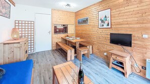 Um espaço compacto com paredes de madeira, uma TV, uma mesa de jantar e um sofá.