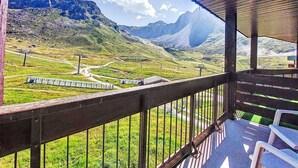 Uma varanda com vista para uma paisagem montanhosa, incluindo uma estrada e uma linha de trem.