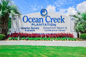 Señal de Ocean Creek Plantation anunciando alquileres vacacionales, un resort frente al mar y un centro de conferencias.