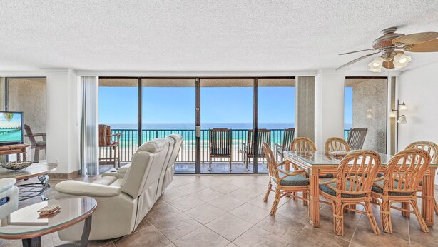 Un vaste espace de vie avec balcon donnant sur l’océan, aménagé avec un canapé, une table à manger et des chaises.