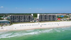 Un hôtel situé en bord de mer, composé de plusieurs bâtiments, doté d’une plage de sable et offrant une vue sur l’océan.