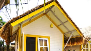 A small, single-story house with a thatched roof, a wooden porch, and a small garden area with stepping stones. - Canggu Castle - Hostel (Tibubeneng)
