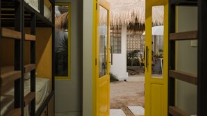 A room with bunk beds, a yellow door, and a thatched roof outside. - Canggu Castle - Hostel (Tibubeneng)
