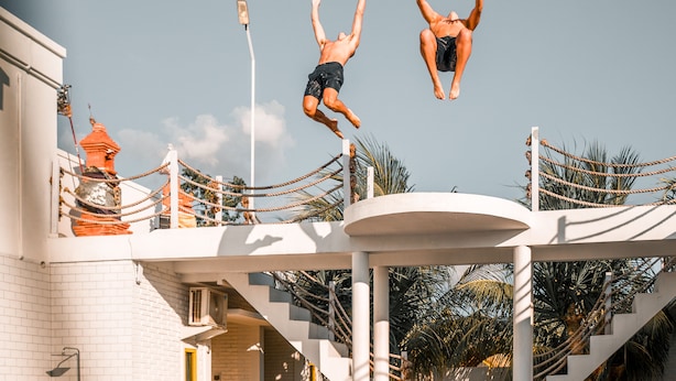 A diving platform with a pool, stairs, and a building with a sign reading "Canggu Castle". - Canggu Castle - Hostel (Tibubeneng)