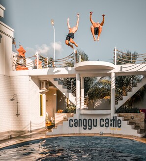 A diving platform with a pool, stairs, and a building with a sign reading "Canggu Castle". - Canggu Castle - Hostel (Tibubeneng)