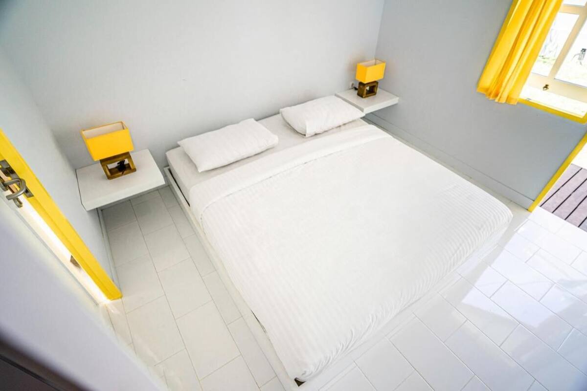 Una camera d'albergo ordinata con un letto, due comodini e una finestra con tende.
