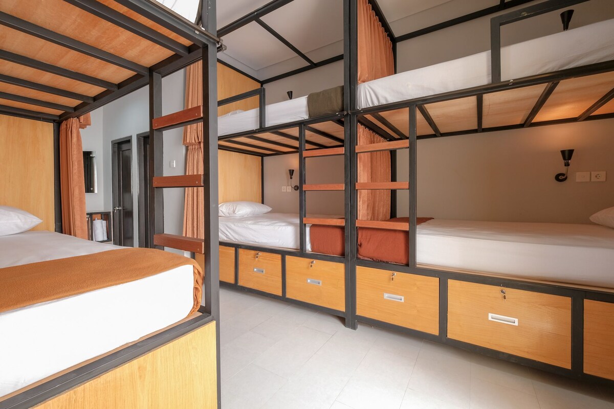 A bunk bed room with wooden frames, a desk, and a chair.