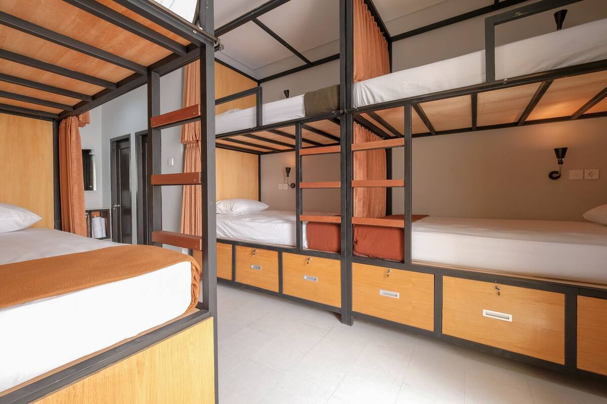 Una stanza con letto a castello, struttura in legno, una scrivania e una sedia.