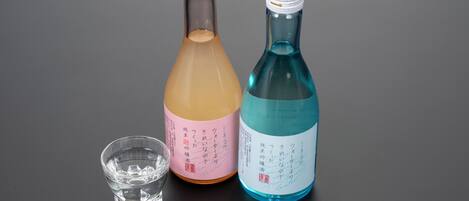Two bottles of beverages and a small glass.