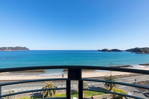 Vista costeira de uma varanda com céu claro, praia e estrada que leva à praia.