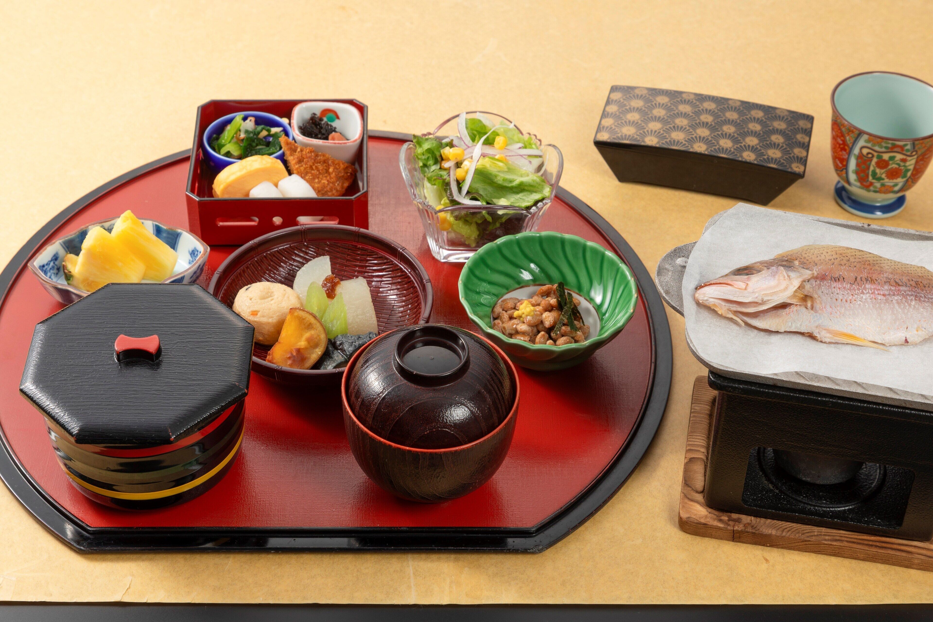 Un repas japonais traditionnel, composé de différents plats et d’un poisson, le tout présenté sur un plateau.