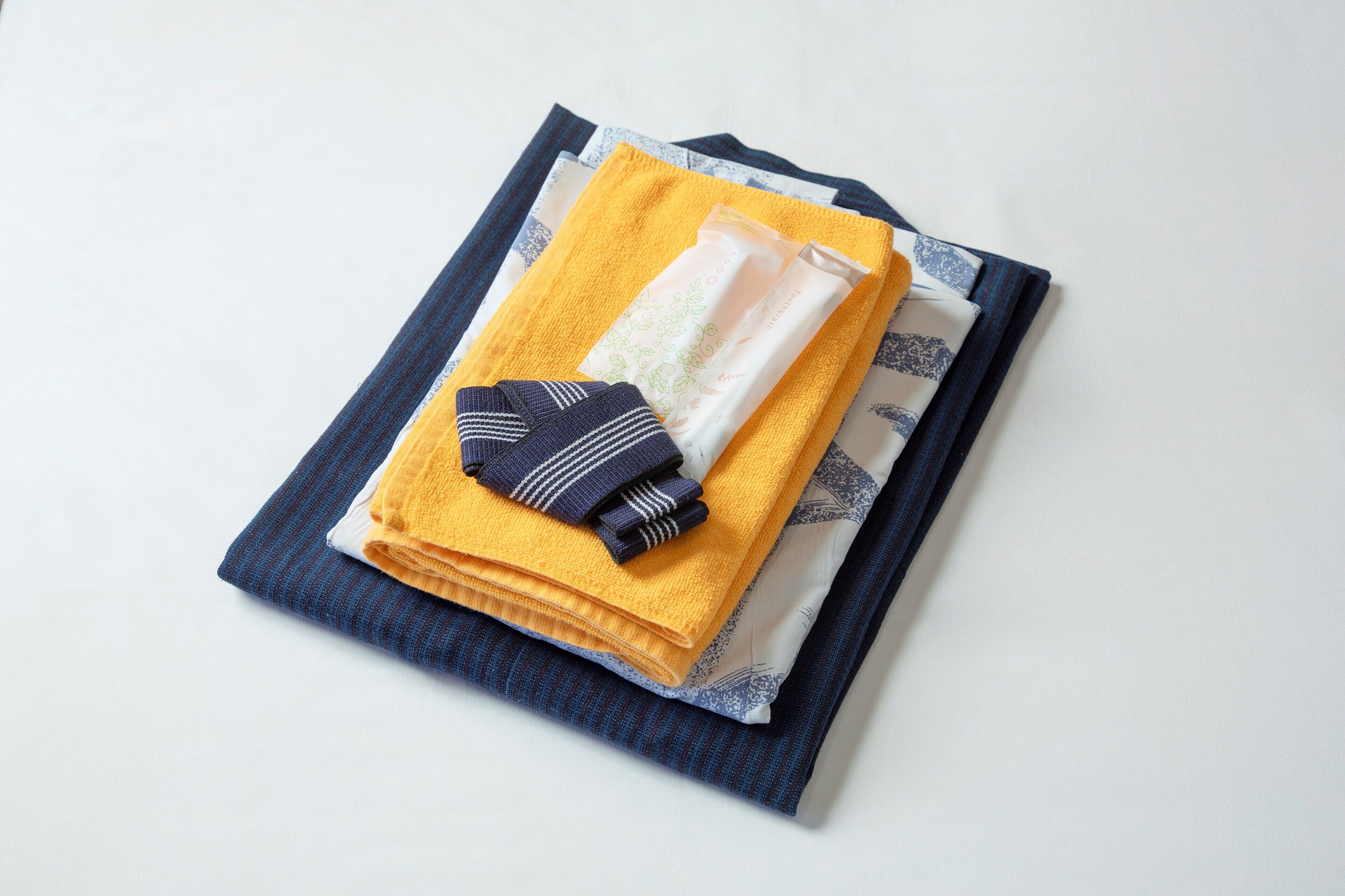 Netjes opgevouwen handdoeken en een opgevouwen kledingstuk op een blauw-witte gestreepte stof.