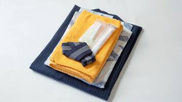 Netjes opgevouwen handdoeken en een opgevouwen kledingstuk op een blauw-witte gestreepte stof.