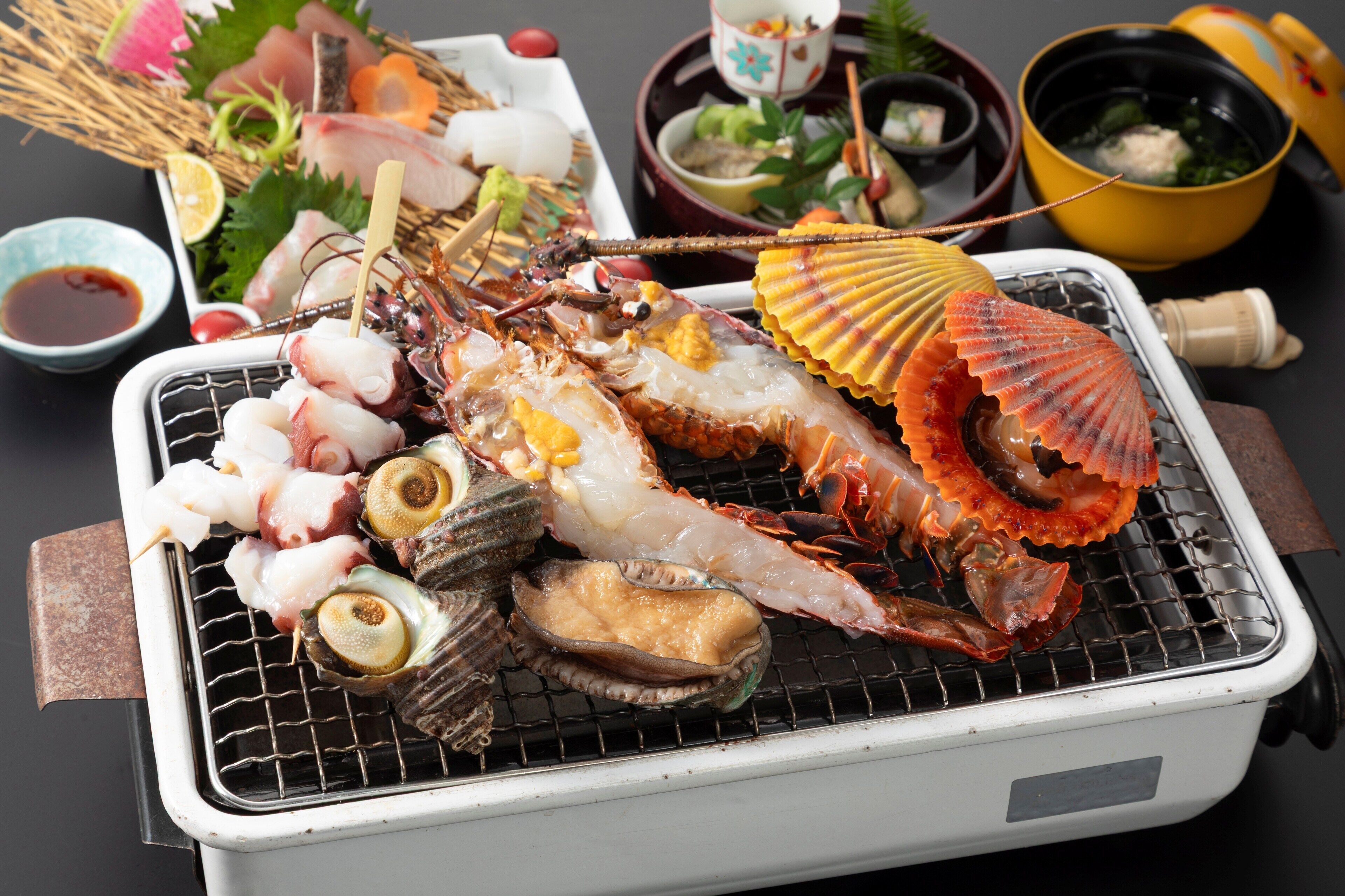 A variety of seafood on a grill, including shrimp, scallops, and lobster.