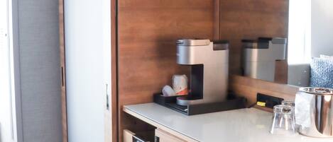 Une salle de bain moderne avec un meuble-lavabo en bois, un miroir et une machine à café.