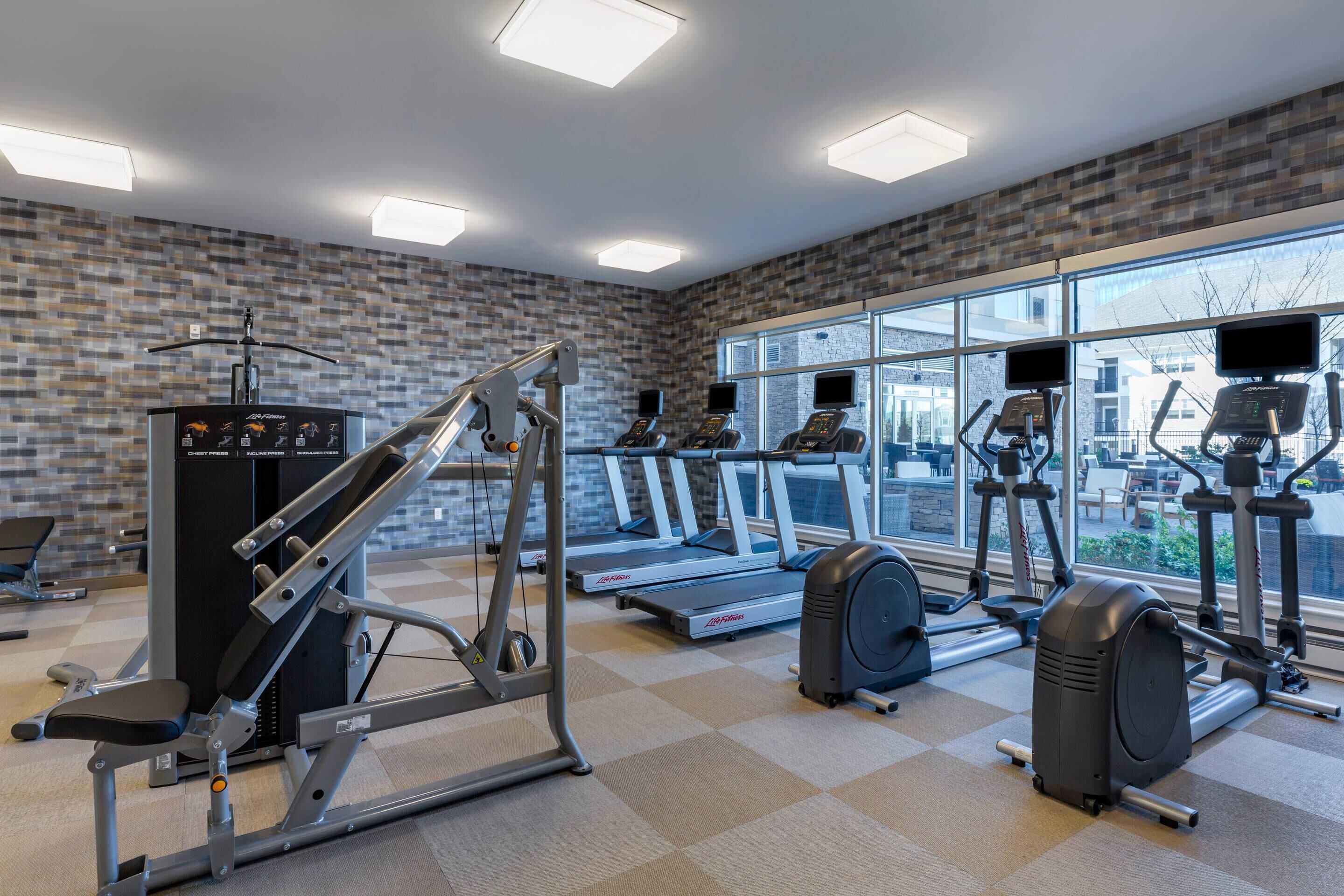 Un gimnasio con cintas de correr, elípticas y equipos de pesas.