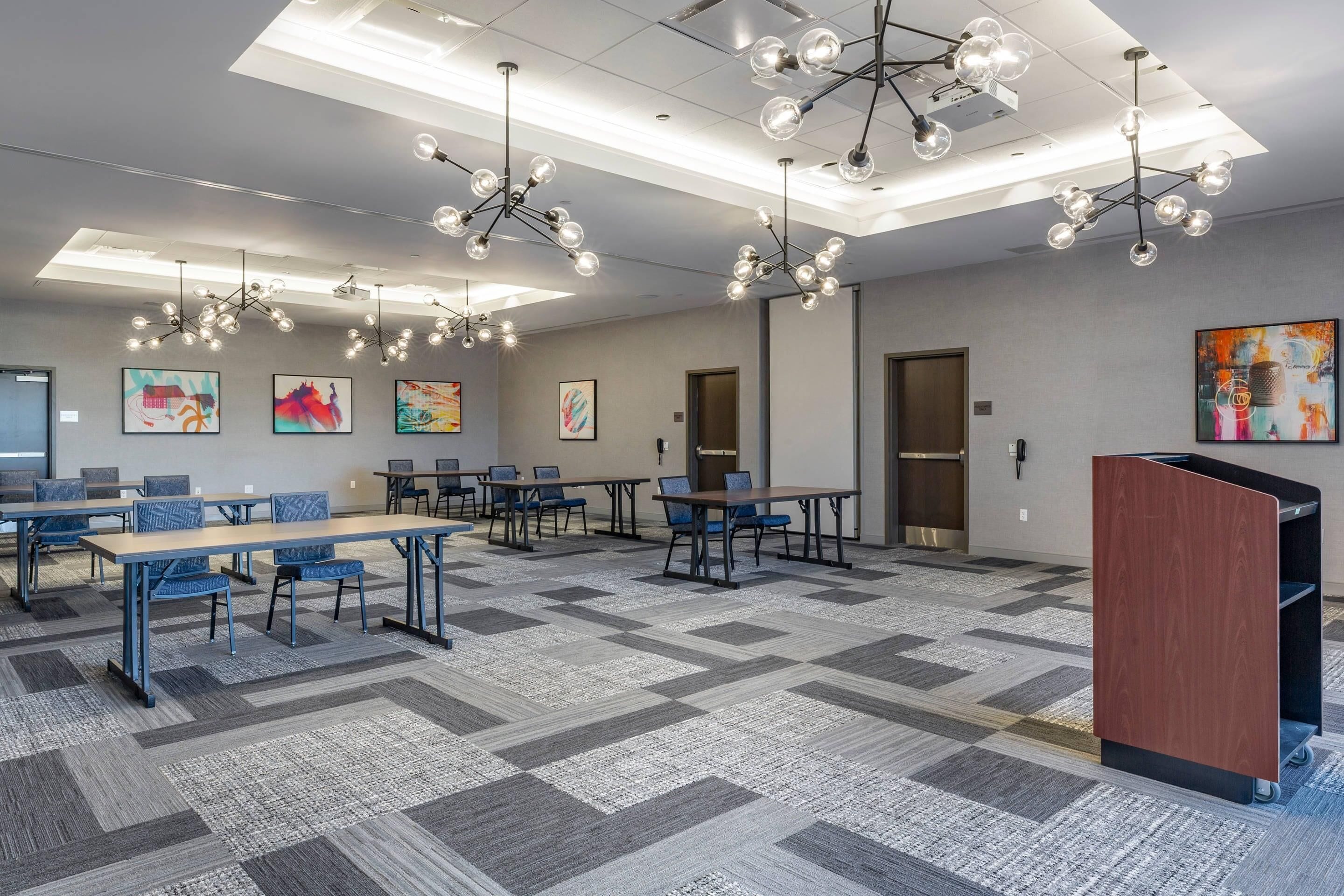 A conference room with tables, chairs, and a podium.