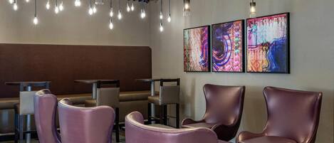 Un interior moderno con asientos, iluminación colgante y arte abstracto en la pared.