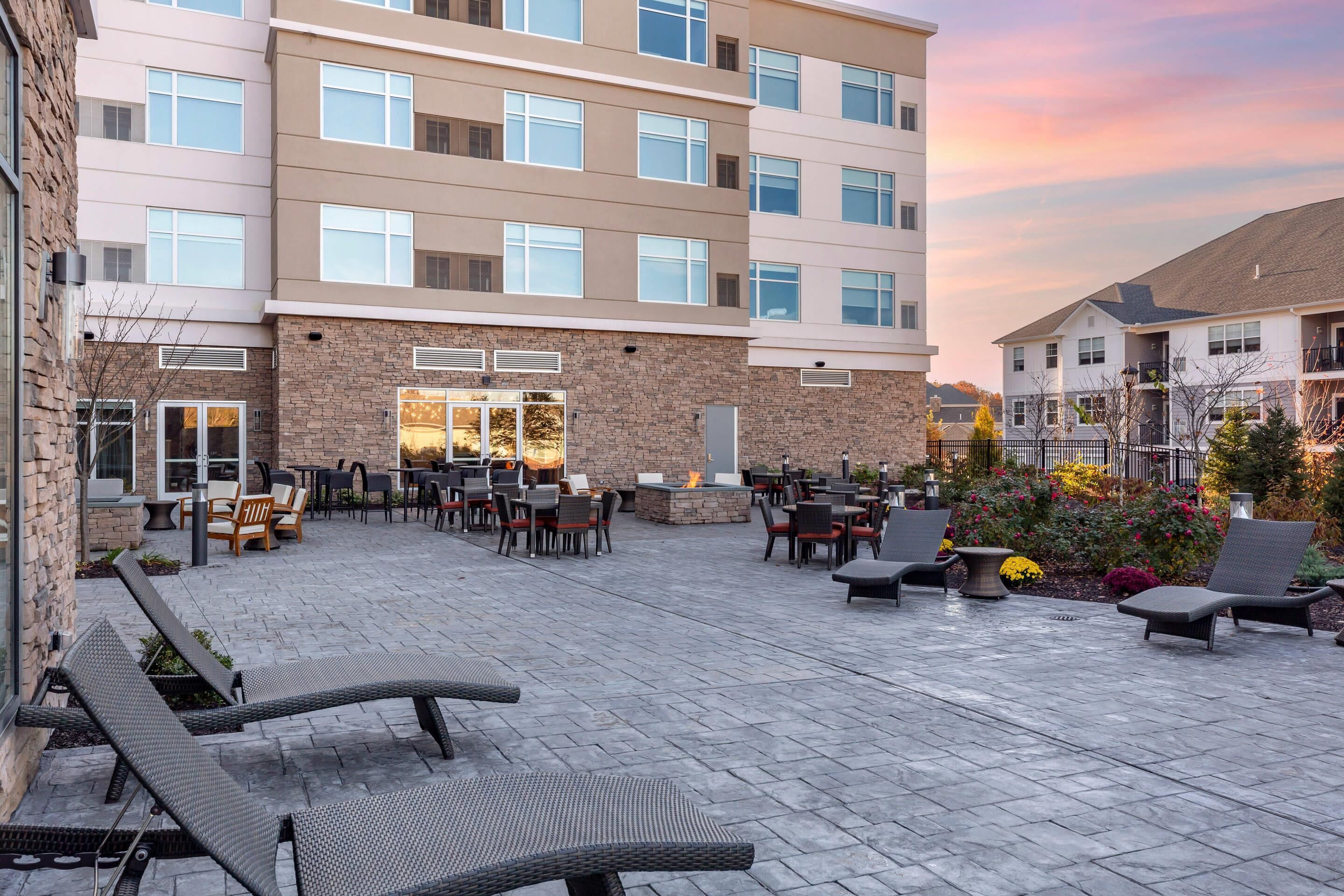 A courtyard with outdoor seating, a fire pit, and a building with multiple windows.