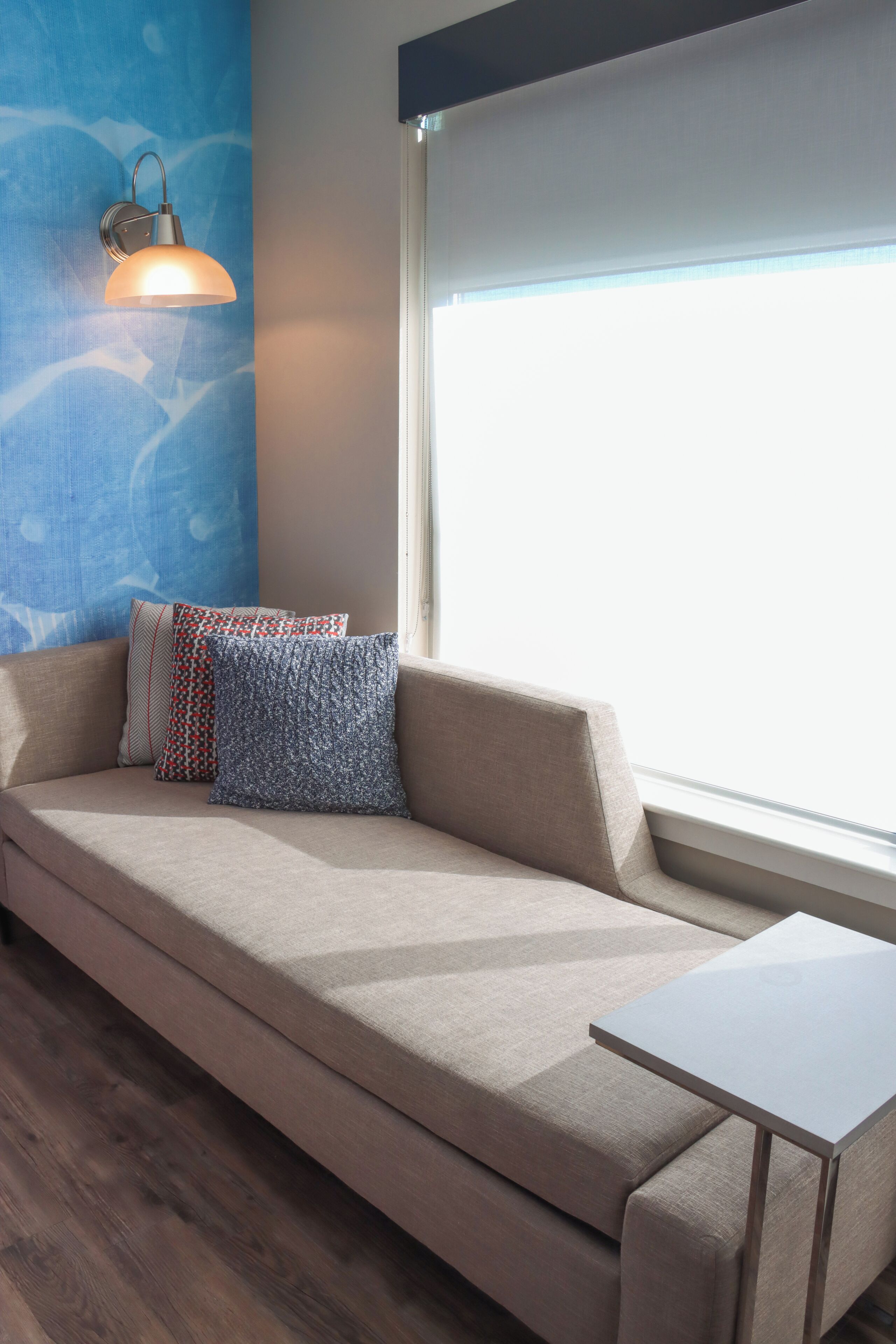 A modern room with a sofa, a small table, and a wall-mounted lamp.